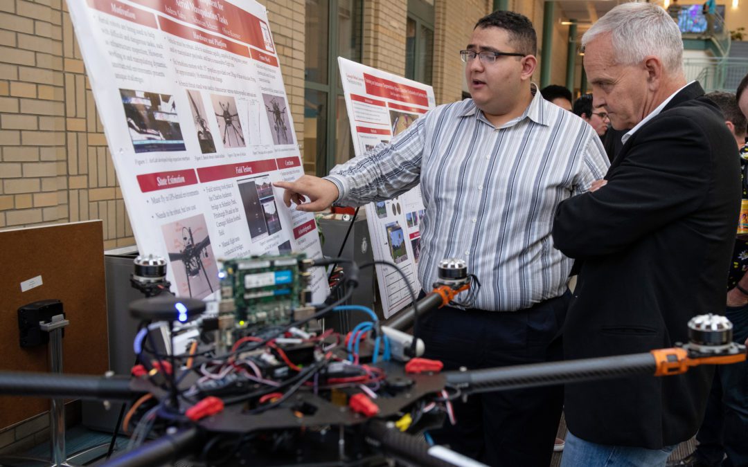 Andrew Saba discusses his robotics research with Dean Martial Hebert during his summer scholars presentation.